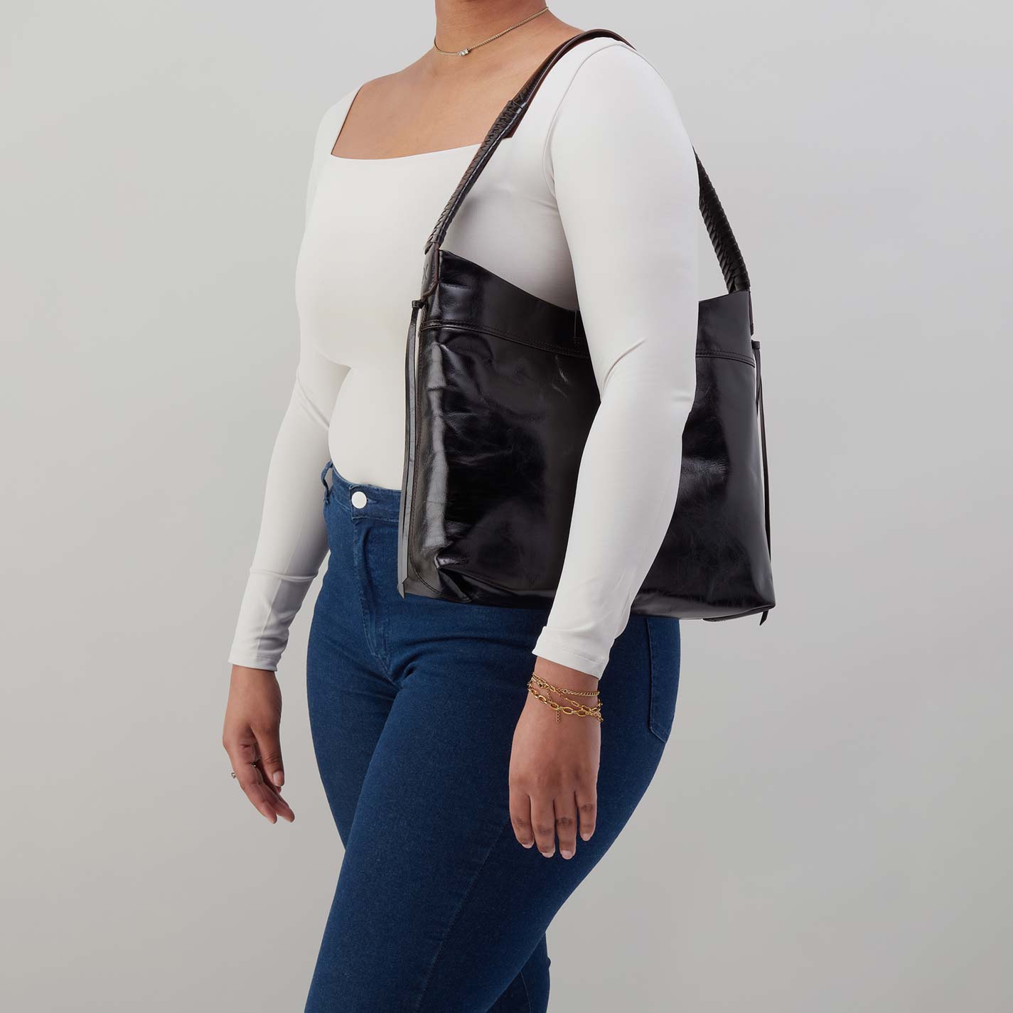 Person wearing a black leather handbag on a plain background