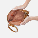 Brown leather handbag held by a hand on a light background