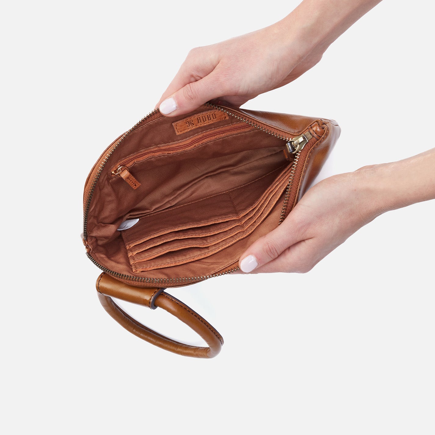 Brown leather clutch held by a hand on a light gray background