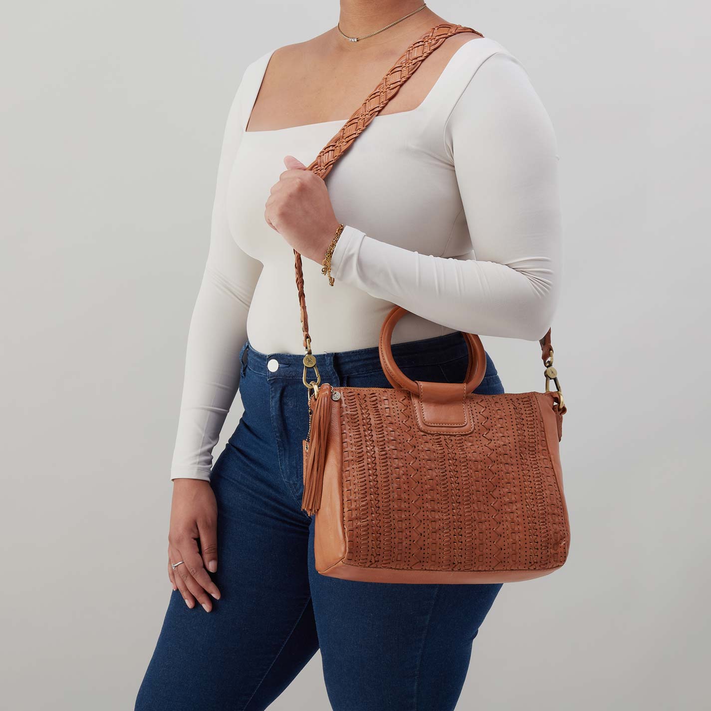 Person holding a brown woven handbag against a plain background