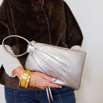 Person holding a silver clutch with a plain background