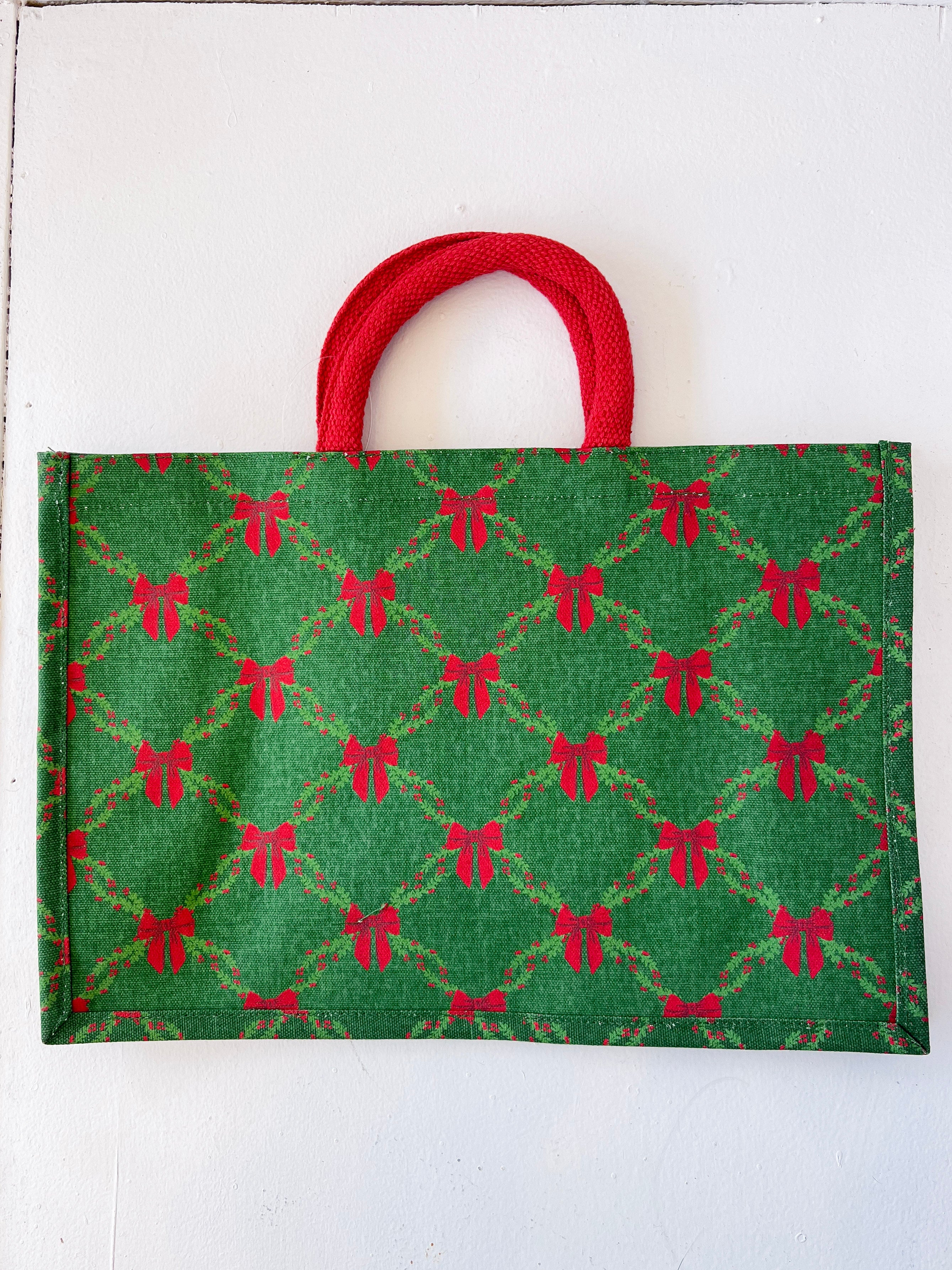 Green fabric bag with red bow pattern and red handle on a white background