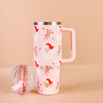Pink travel mug with red fox design on a beige background