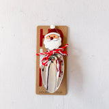 Metal scoop with Santa Claus design on a cardboard backing against a white background