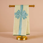 Towel with a decorative bow on a gold towel rack against a beige background