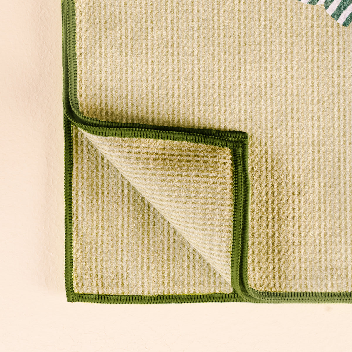Close-up of a textured green and beige fabric with a folded corner on a light background