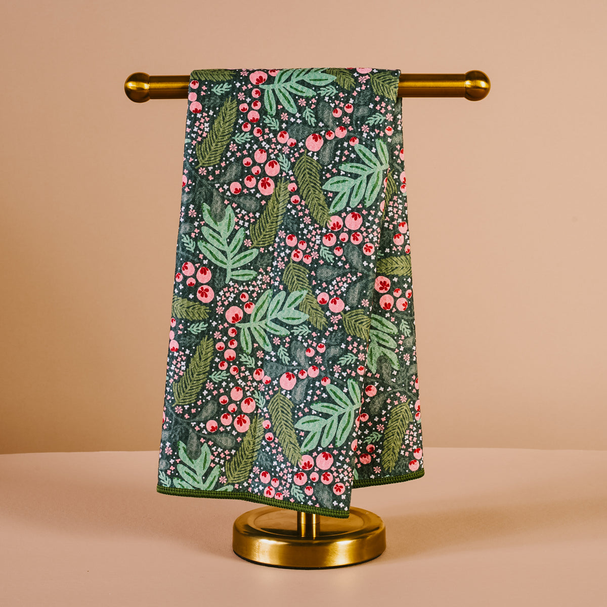Floral patterned towel hanging on a gold towel rack against a beige background