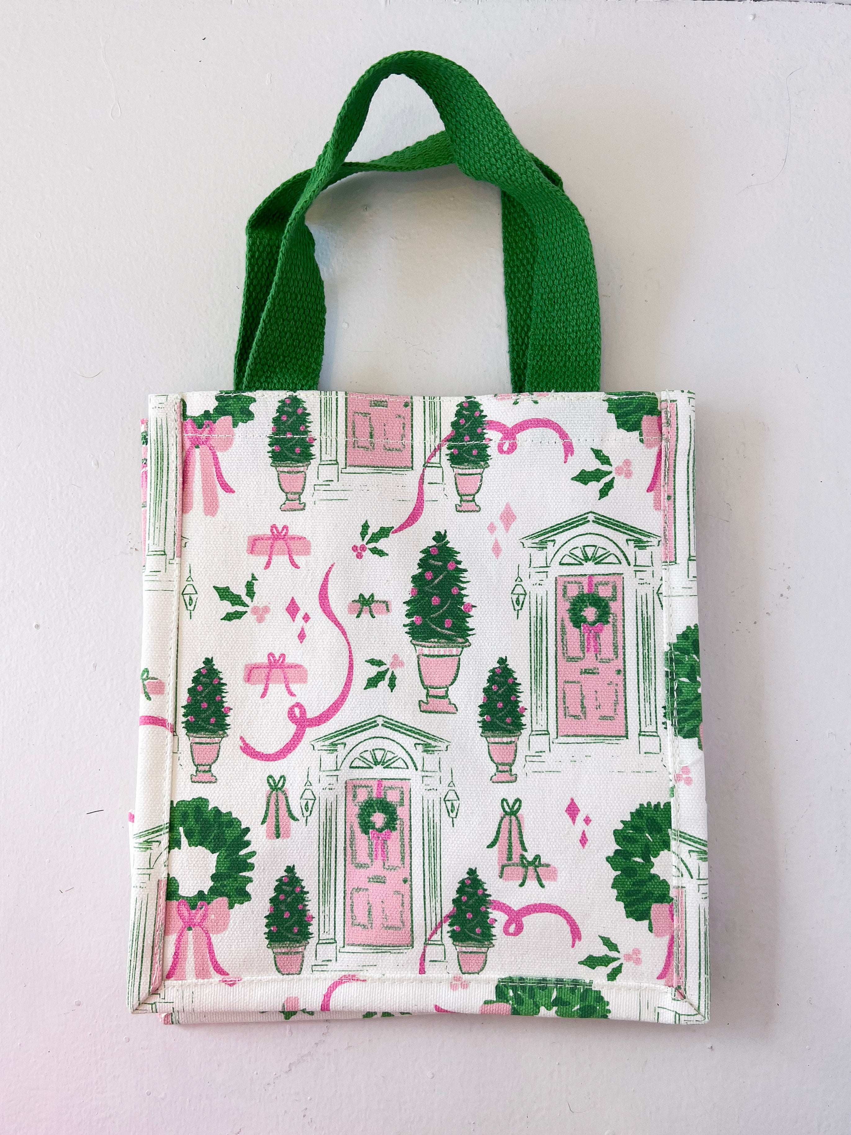 Small tote bag with festive design featuring doors, wreaths, and ribbons on a white background