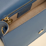 Close-up of a blue handbag with gold accents on a beige background