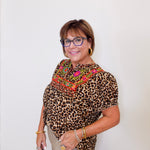 Woman wearing a leopard print top with colorful embroidery against a white background