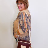 Woman holding a brown handbag against a white wall