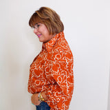 Woman wearing an orange patterned shirt against a white background