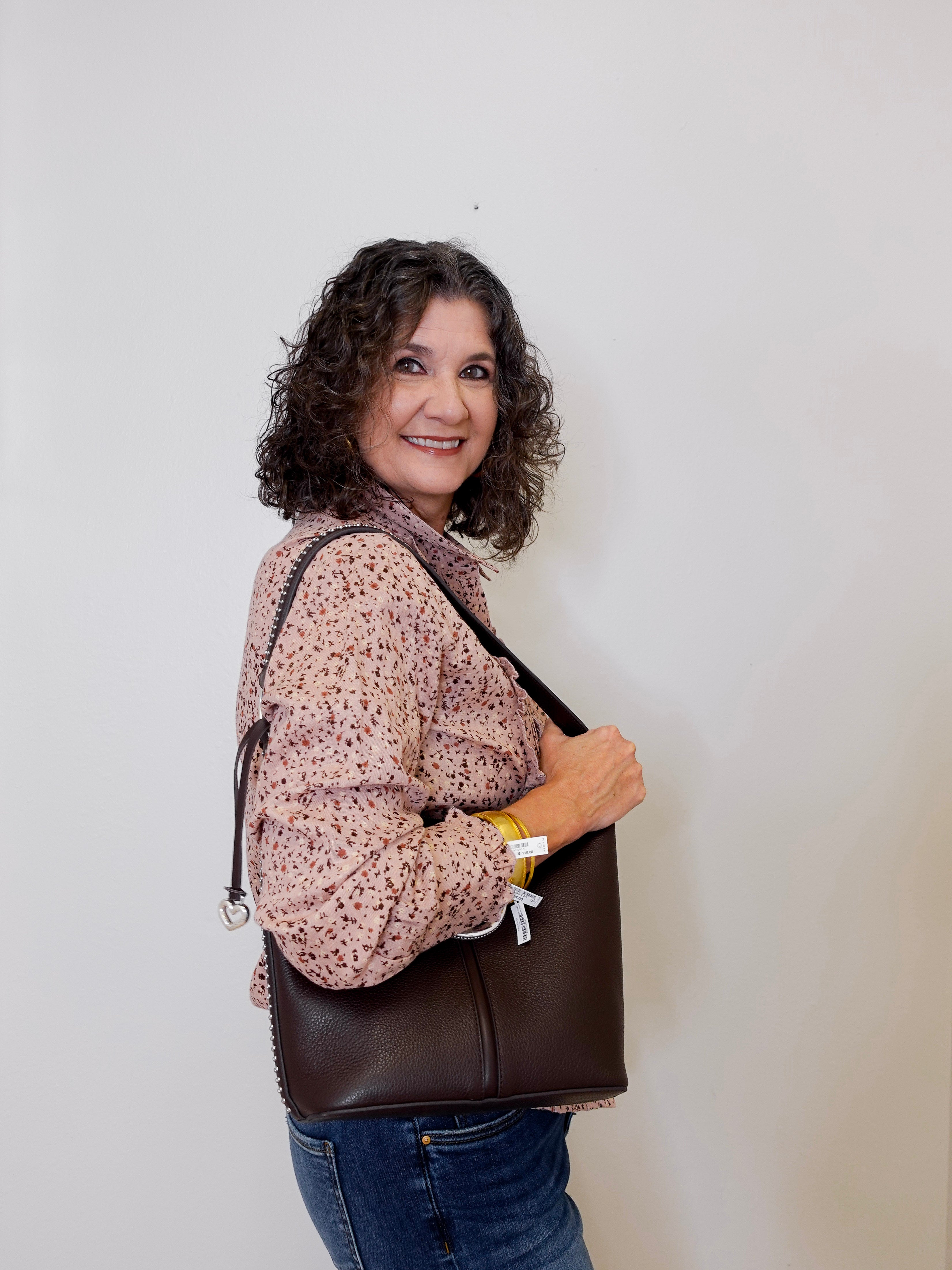 Woman holding a brown leather bag against a plain background