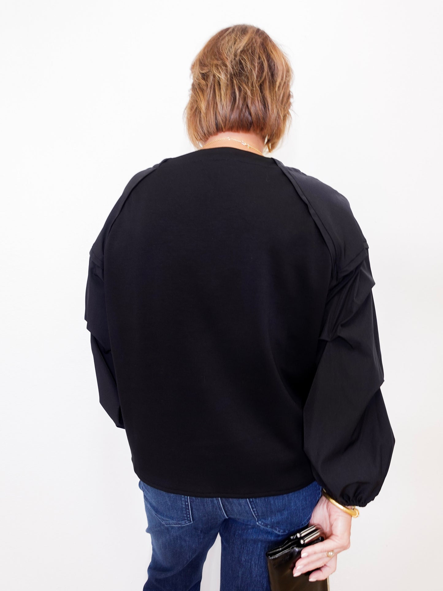 Person wearing a black jacket and blue jeans on a white background