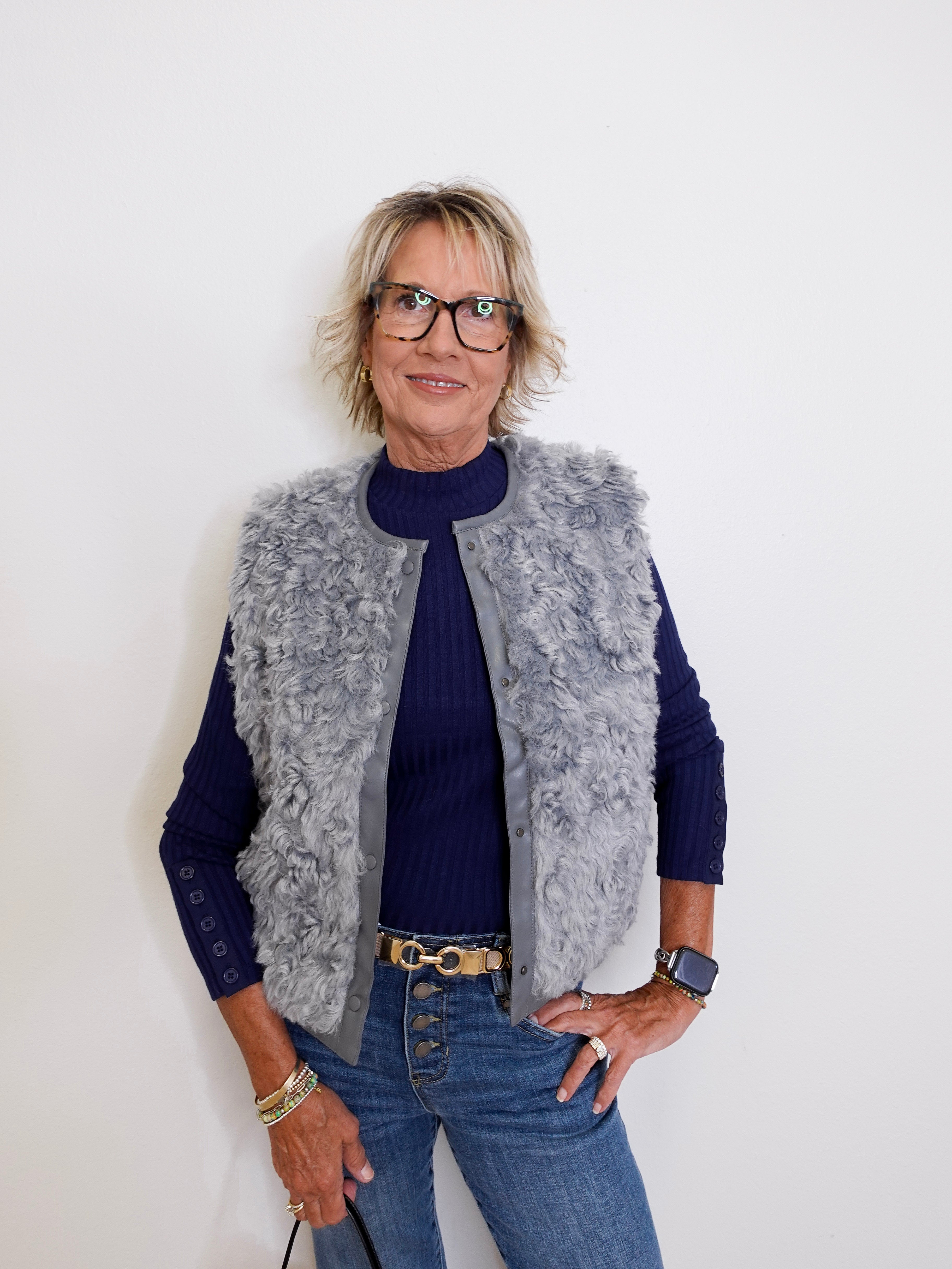 Person wearing a gray vest over a blue shirt with a white background