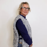Woman wearing a navy sweater and gray cardigan against a white background