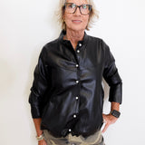 Person wearing a black leather jacket and camouflage pants against a white background