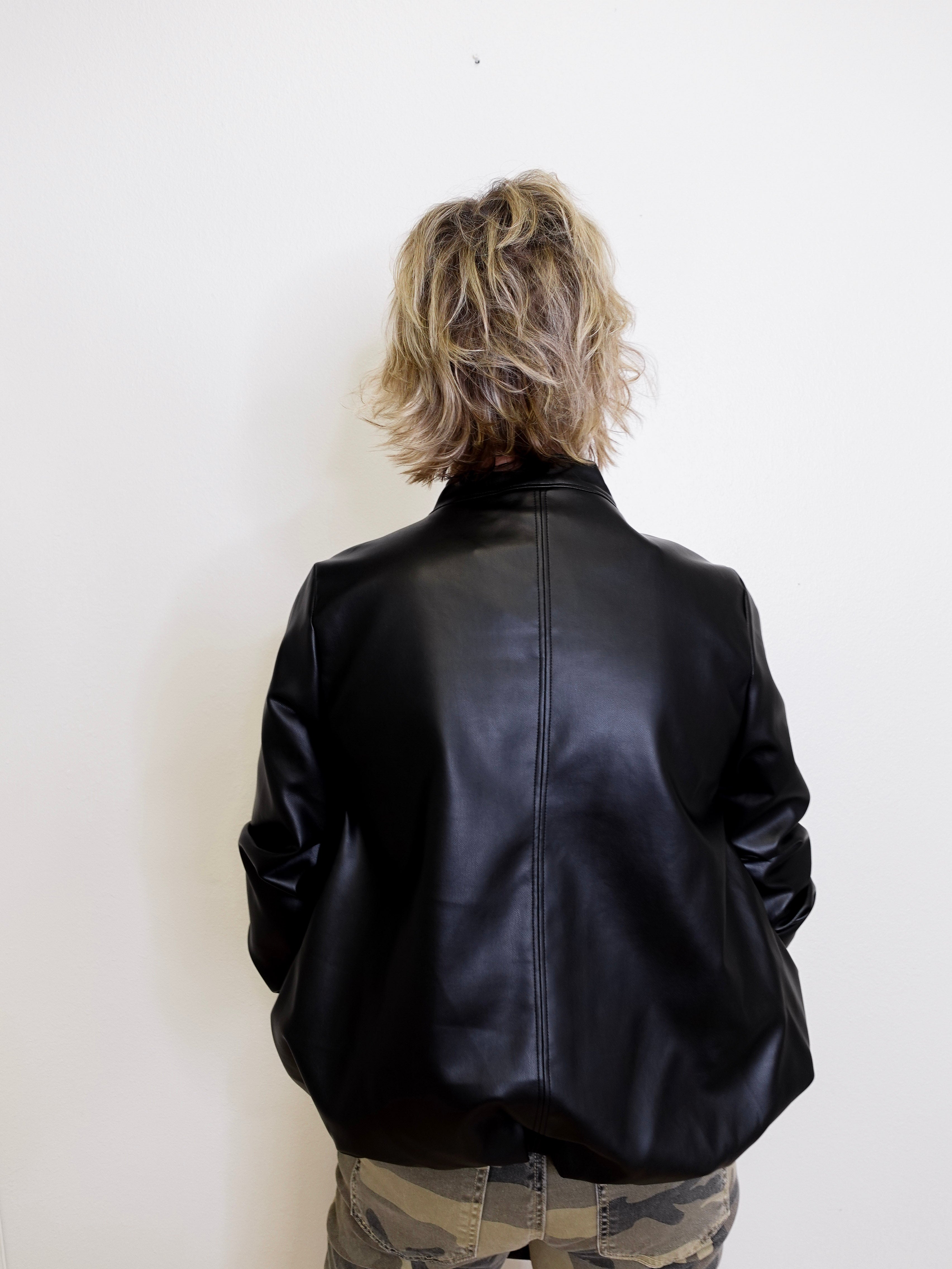 Person wearing a black leather jacket against a white background