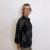 Person wearing a black jacket and camouflage pants against a white background