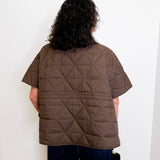 Person wearing a brown quilted jacket against a white background