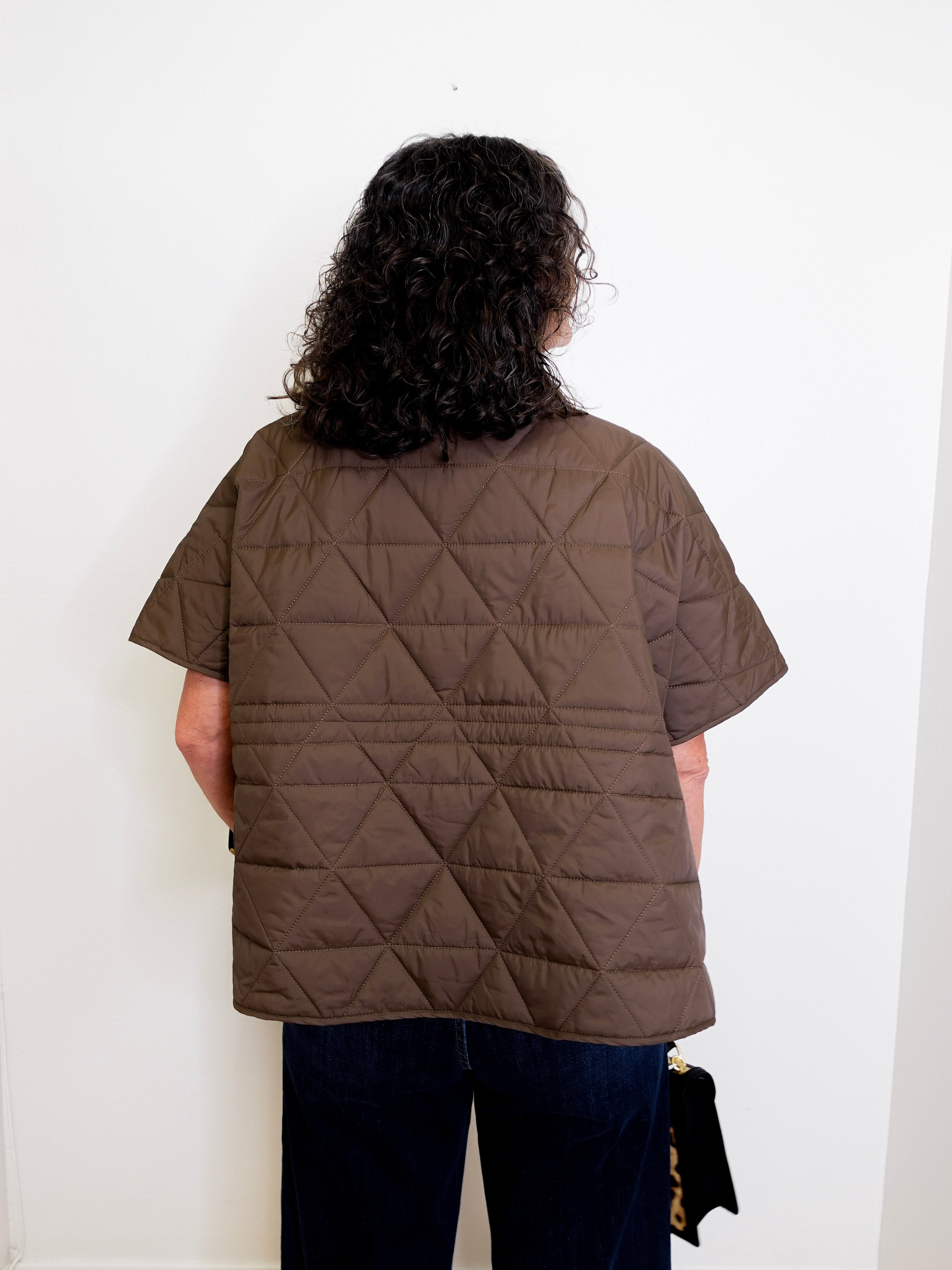 Person wearing a brown quilted jacket against a white background