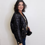 Woman wearing a black quilted jacket against a white wall