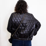 Person wearing a black quilted jacket with a white background