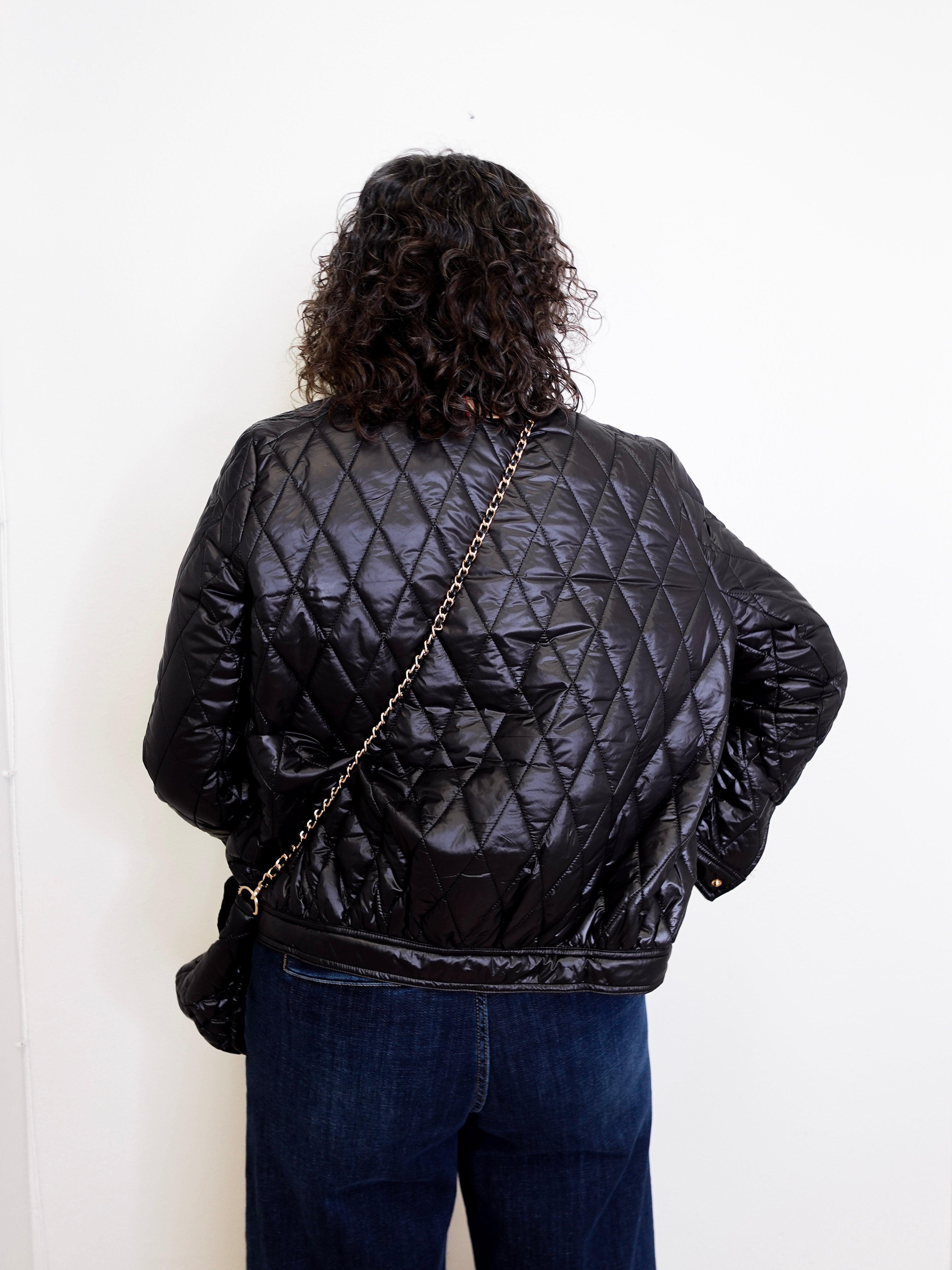 Person wearing a black quilted jacket with a white background