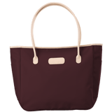Maroon tote bag with beige handles and trim on a transparent background