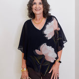 Woman wearing a black floral blouse against a white background