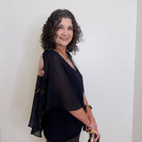 Woman wearing a black outfit with cut-out shoulders against a white background