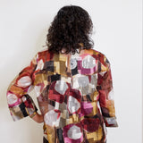 Person wearing a colorful patterned jacket against a white background