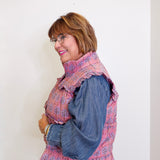 Woman wearing a pink floral blouse with denim sleeves against a white background