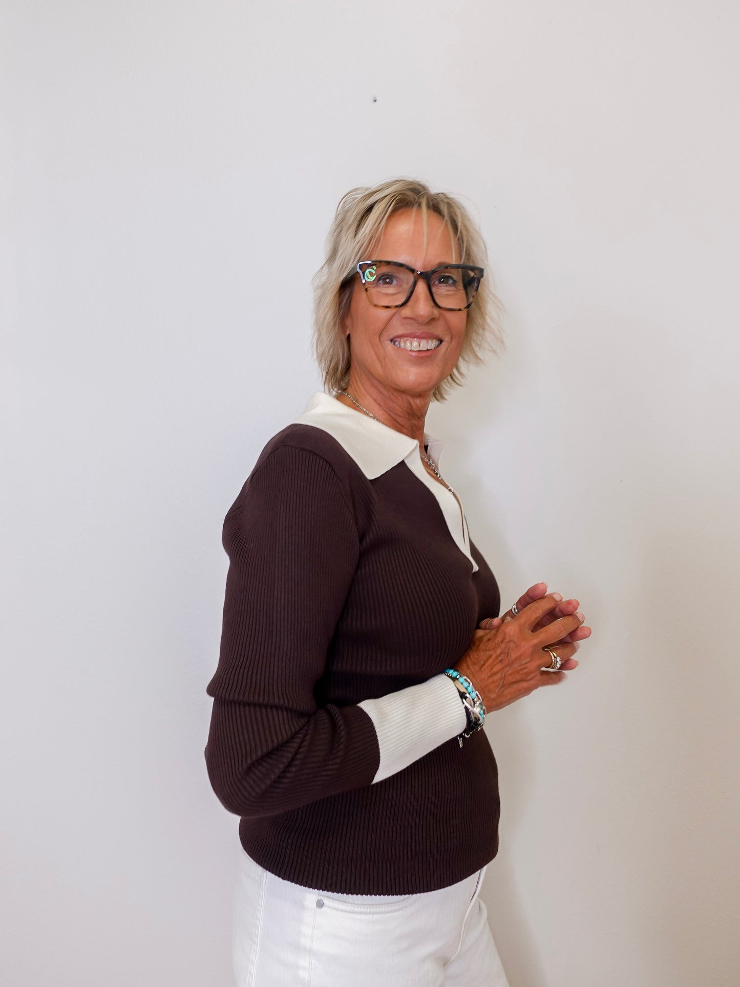 Woman wearing a brown and white sweater against a plain background