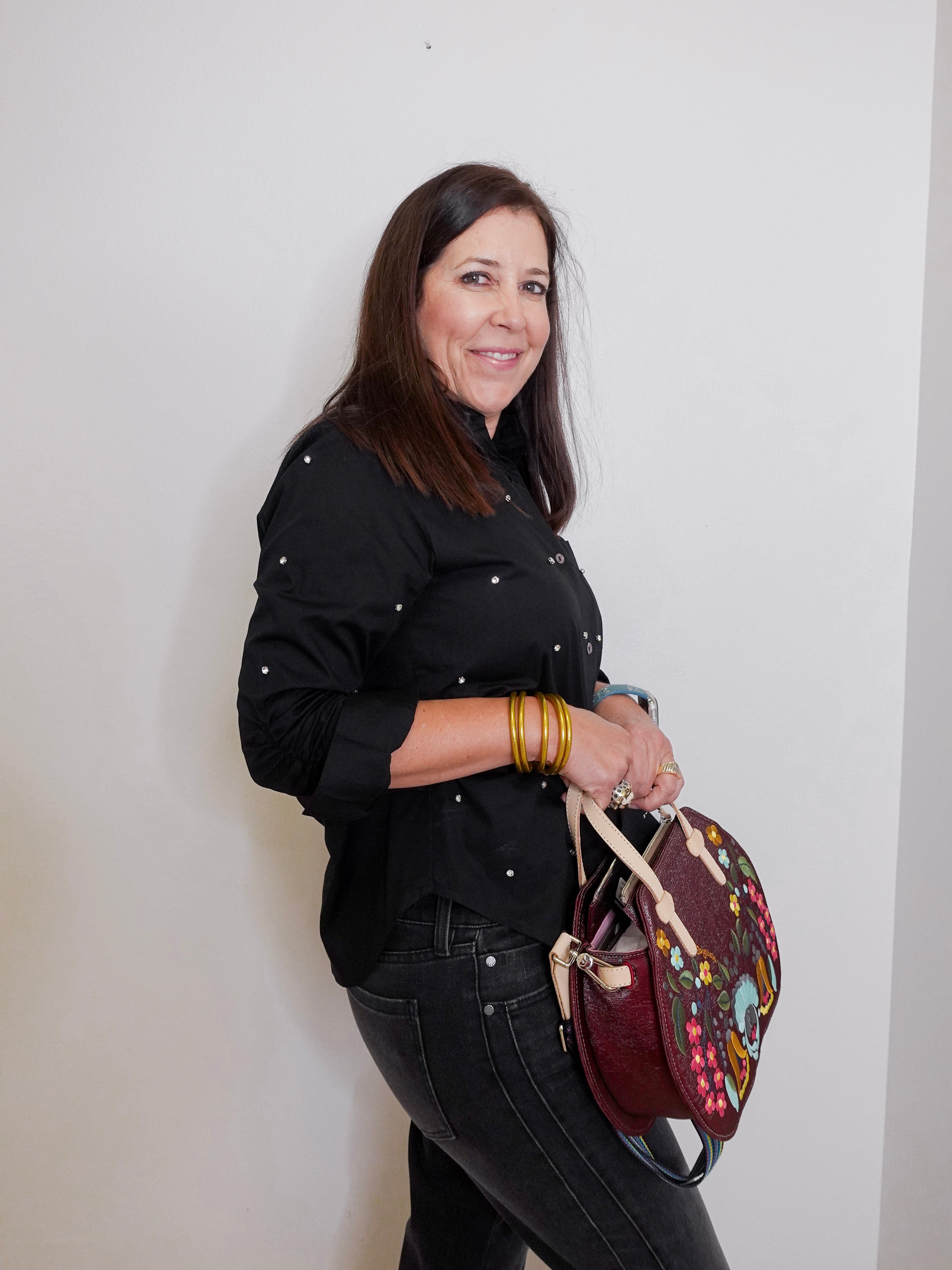 Woman holding a colorful backpack against a plain background