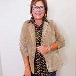 Woman wearing a beige blazer over a leopard print shirt with a white background