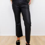 Person wearing black pants and green shirt against a white wall