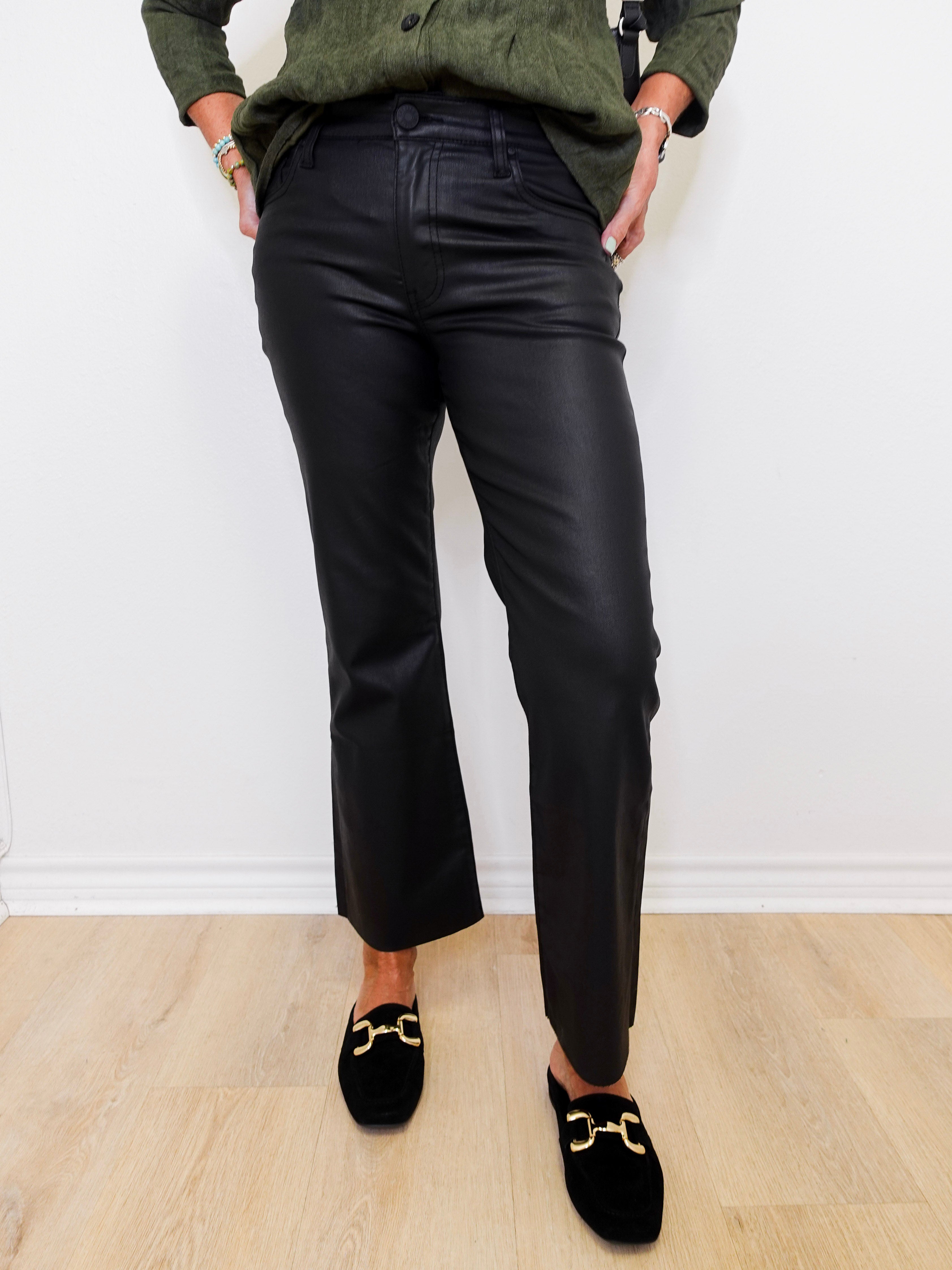 Person wearing black pants and green shirt against a white wall