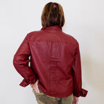 Person wearing a red leather jacket and camouflage pants against a white background