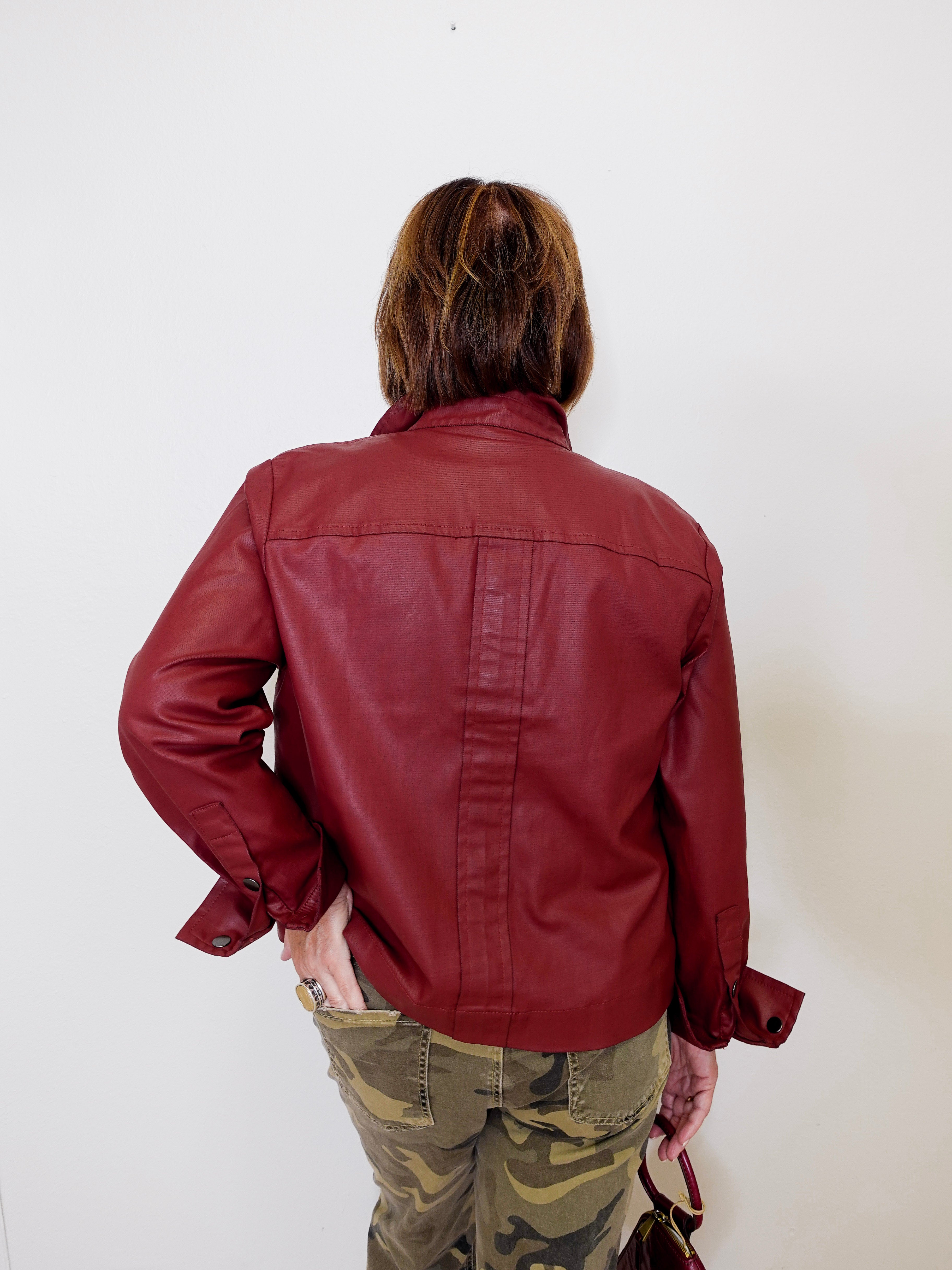 Person wearing a red leather jacket and camouflage pants against a white background