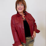 Woman wearing a red leather jacket and camouflage pants against a white background