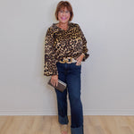 Person wearing a leopard print top and blue jeans against a plain background