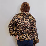 Person wearing a leopard print blouse against a plain background