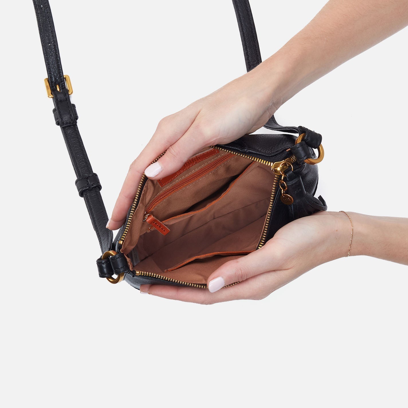 Hand holding a black handbag with gold accents on a white background
