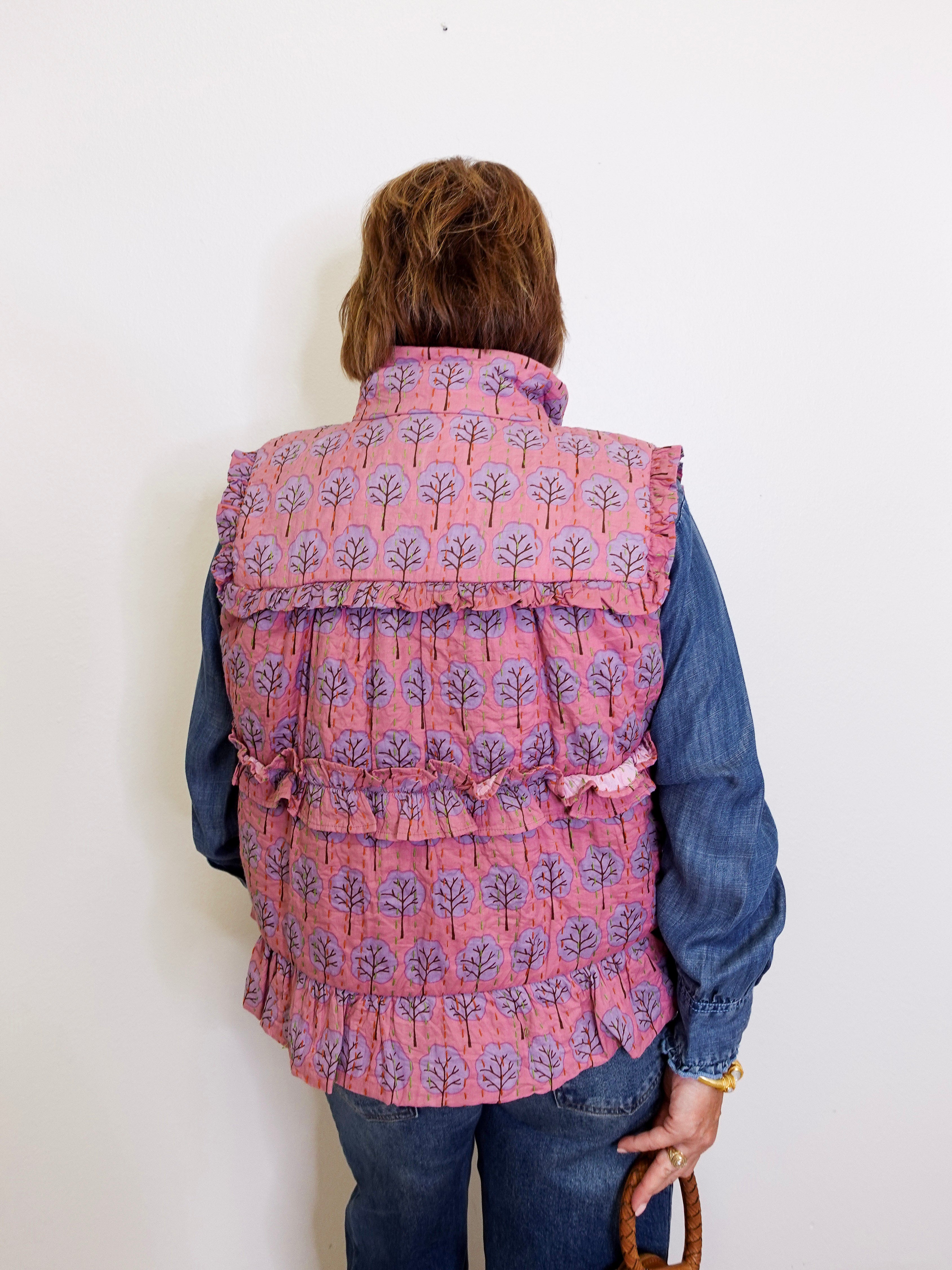 Person wearing a pink patterned vest over a blue shirt against a white background