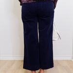 Person wearing navy blue pants with a patterned top on a white background