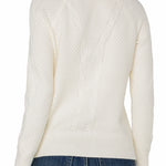 White cable knit sweater worn by a person on a white background