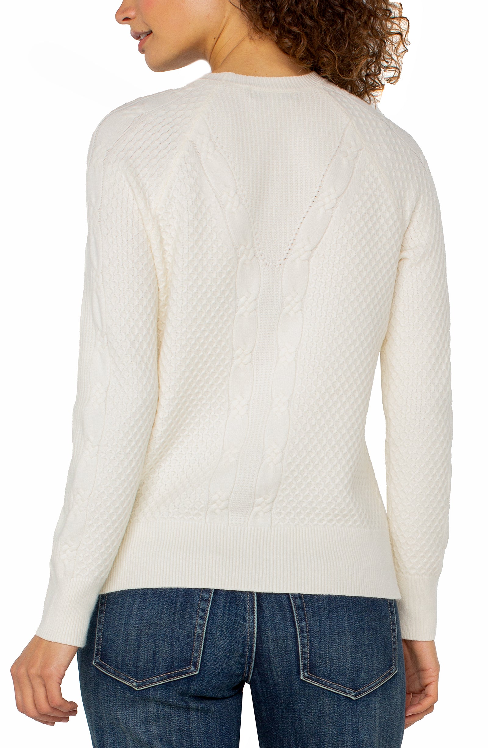 White cable knit sweater worn by a person on a white background