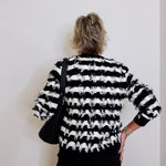 Person wearing a black and white striped sweater with a plain background