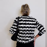 Person wearing a black and white striped sweater with a plain background